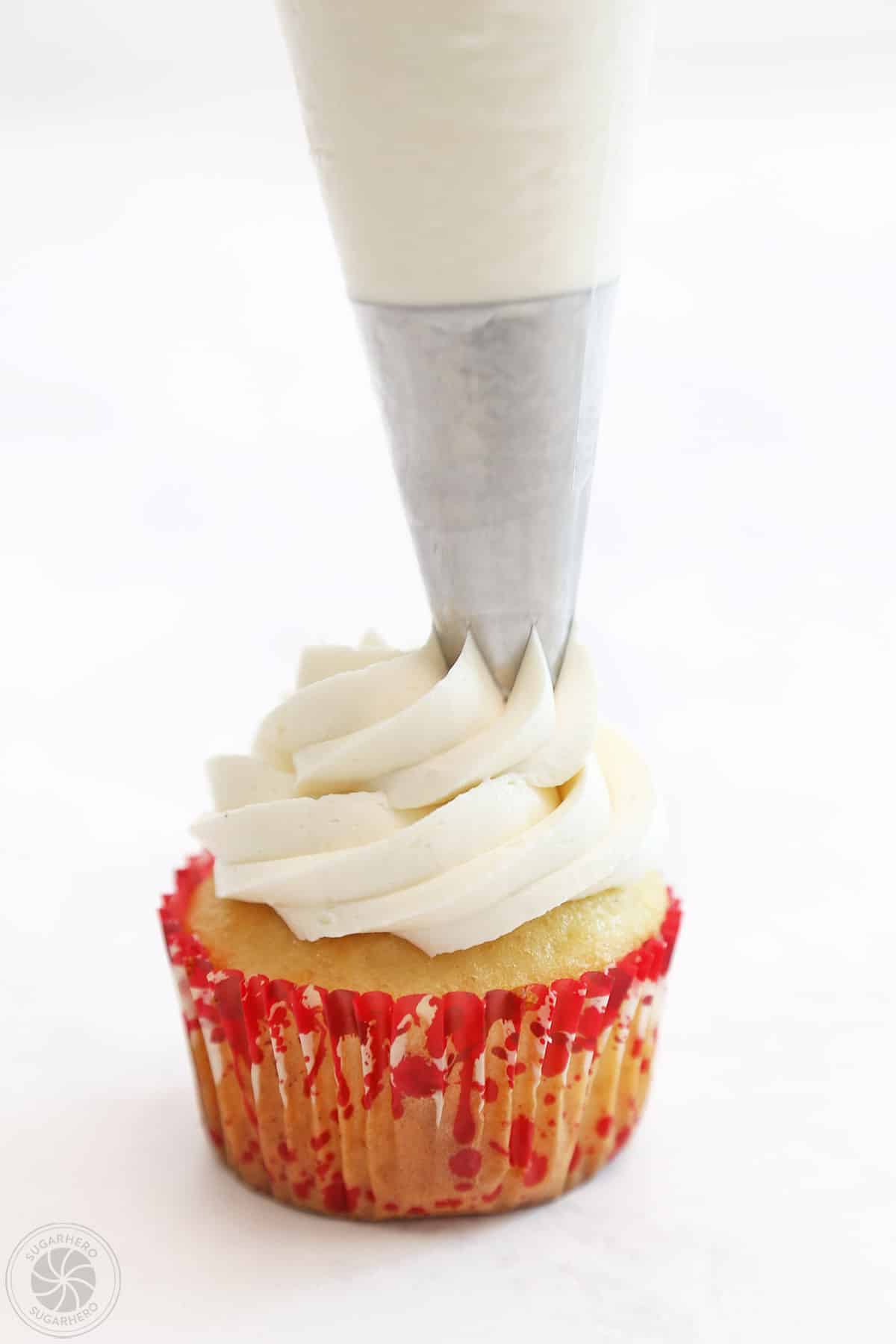 Piping white buttercream on a cupcake.