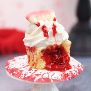 Close up of a vampire bite cupcake that's cut in half with oozing red filling.