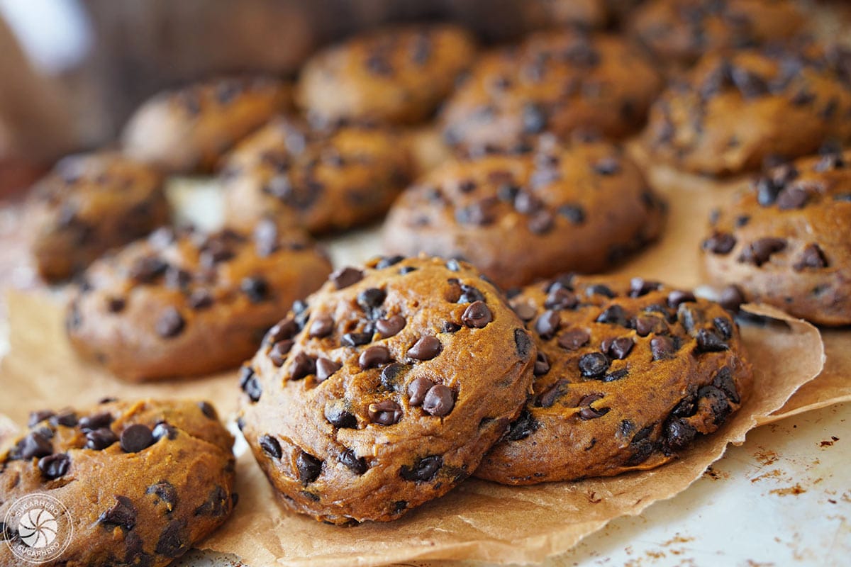 Several pumpkin chocolate chip cookies on parchment paper.