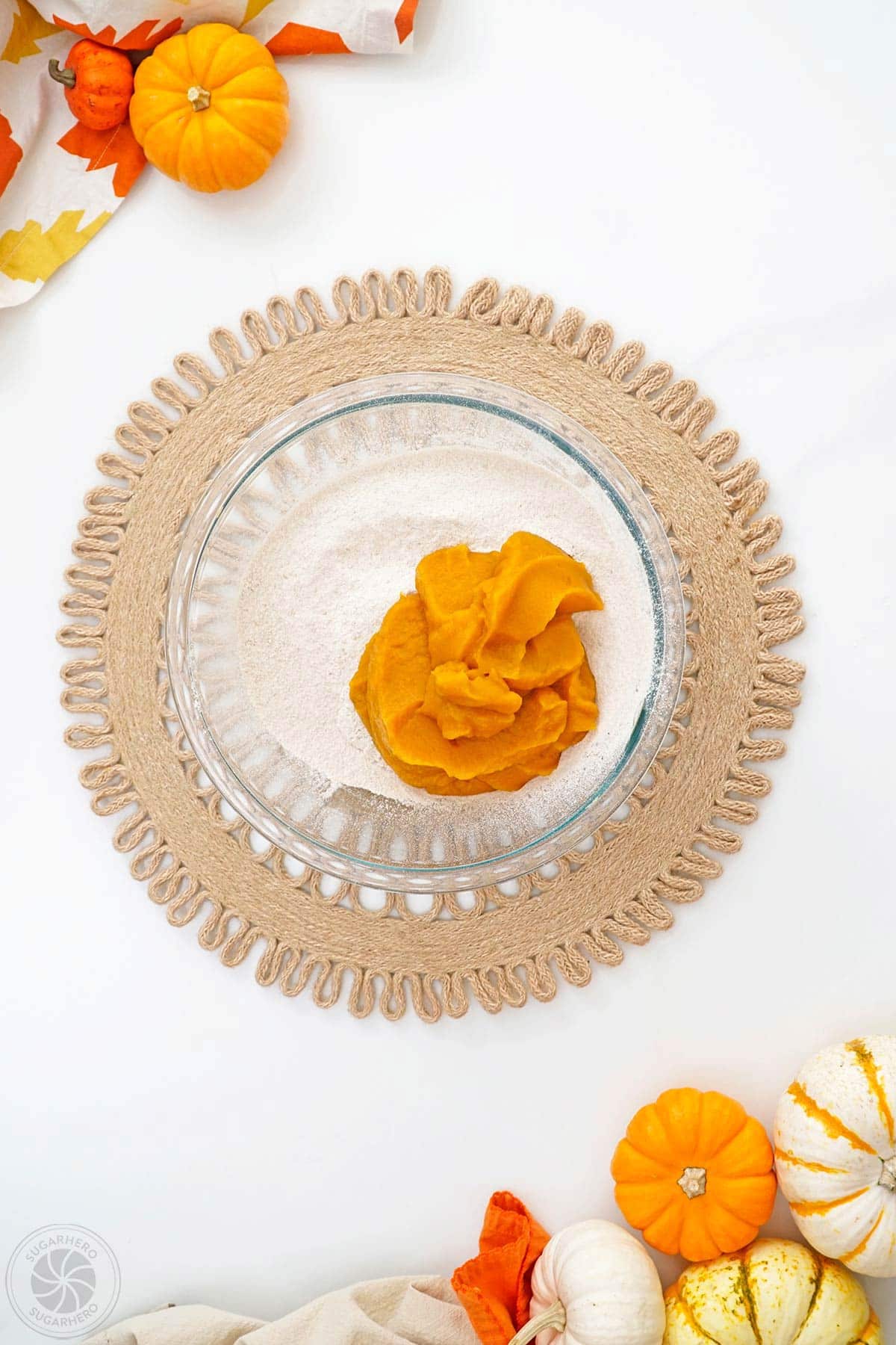 Adding pumpkin puree to cake mix in a mixing bowl.
