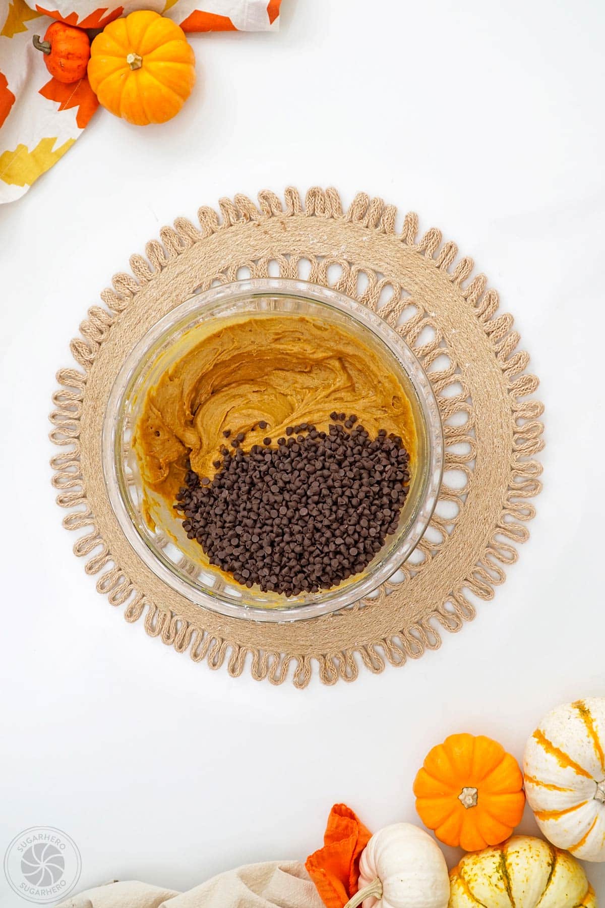 Mini chocolate chips added to a bowl of pumpkin cookie batter.