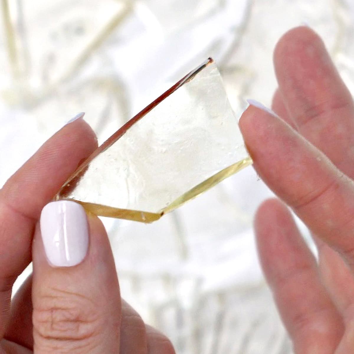 Close-up of hands displaying a piece of edible sugar glass.