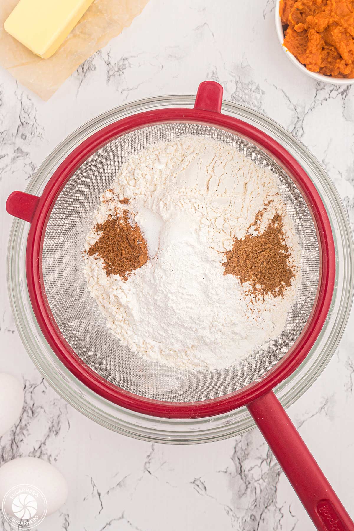 Sifting dry ingredients into a glass bowl.