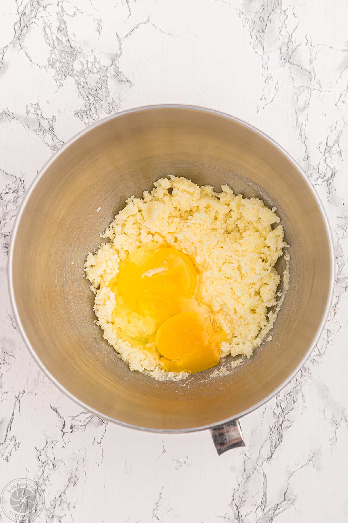 Eggs added to creamed butter and sugar in a mixing bowl.