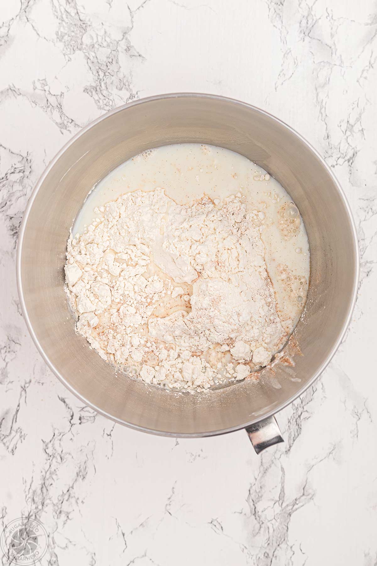 Adding milk and dry ingredients to cupcake batter in a mixing bowl.