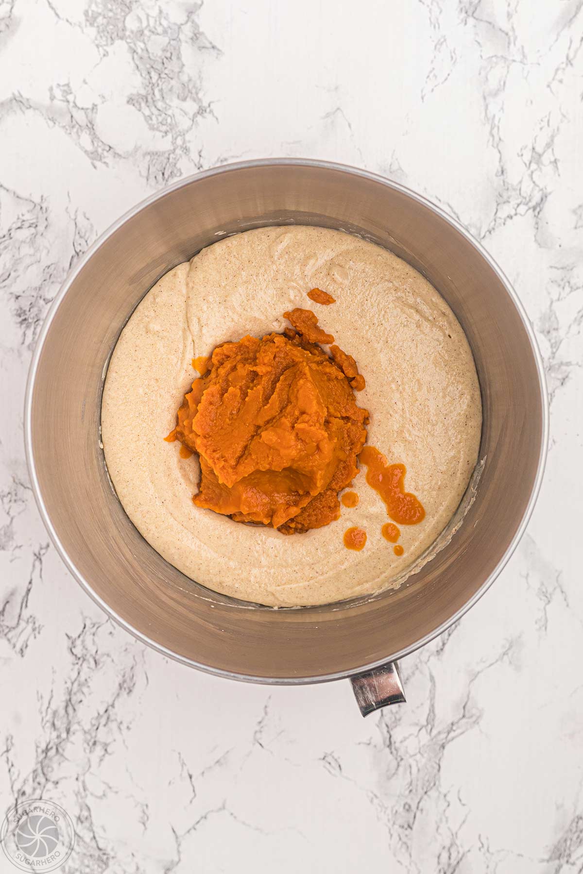 Pumpkin puree added to cupcake batter in mixing bowl.