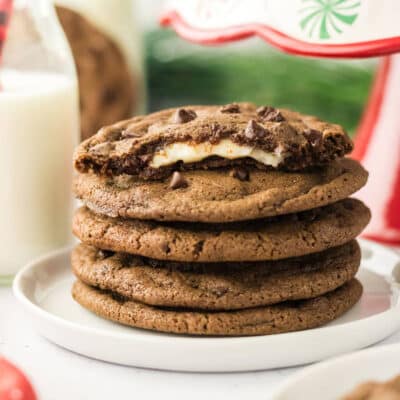 Five chocolate peppermint cheesecake stuffed cookies stacked one on top of the other with a bite removed from the top cookie.