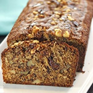 Close up of a slice of banana bread leaning up against the rest of the loaf.