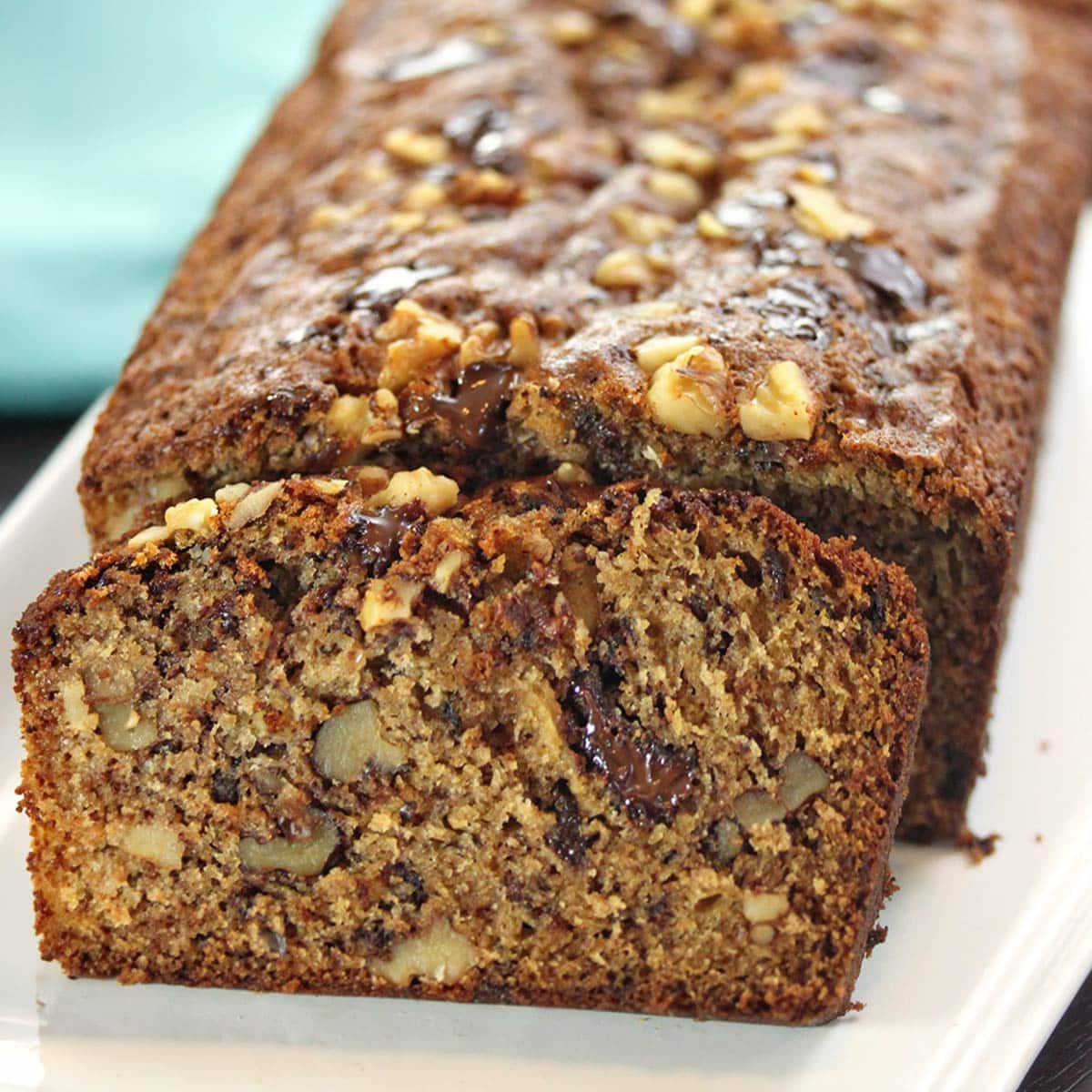 Close up of a slice of banana bread leaning up against the rest of the loaf.